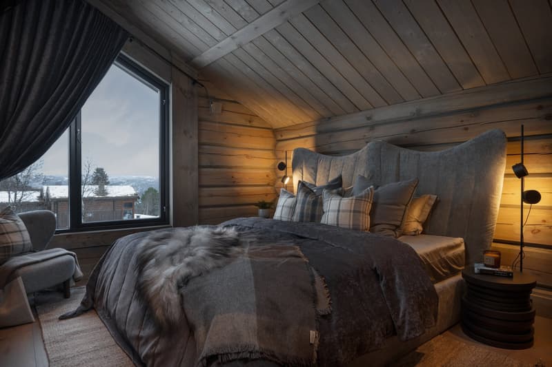 large bed, wooden walls, rug, large window, grey armchair