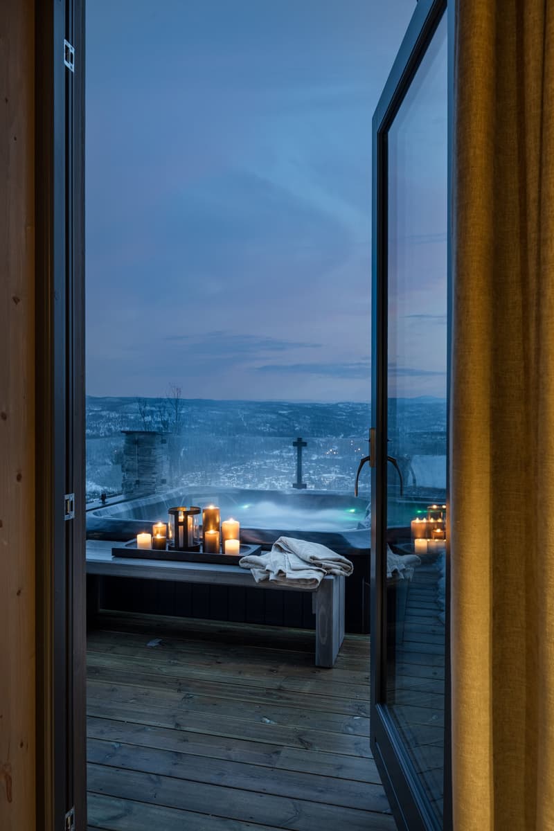 outdoor balcony with wooden deck, hot tub, candle lighting, wooden bench, scenic mountain view