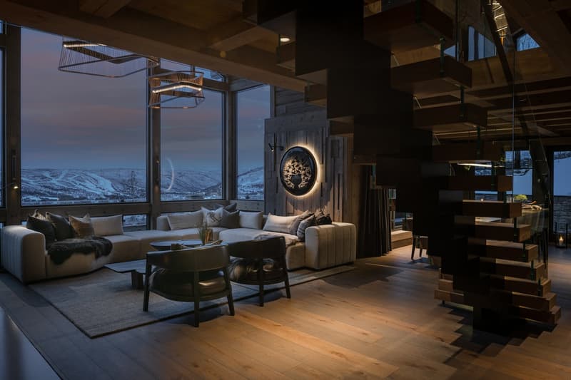 modern style living room with a couch, two armchairs, center table, carpet, wooden floor, large windows, wooden stairs, wooden ceiling, large round wood panel with design