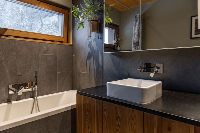 Bathroom with bathtub, sink, mirror, and window