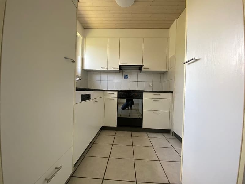 fully equipped kitchen with appliances, white cupboards, tiled floor, light
