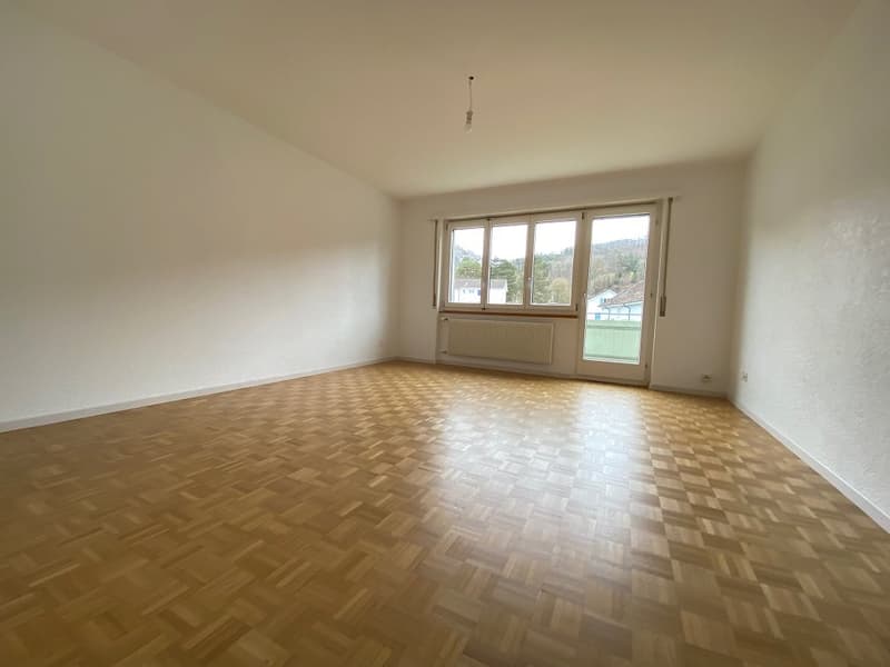 large empty room, white walls, wooden floor, sliding glass door, window, small balcony, radiator