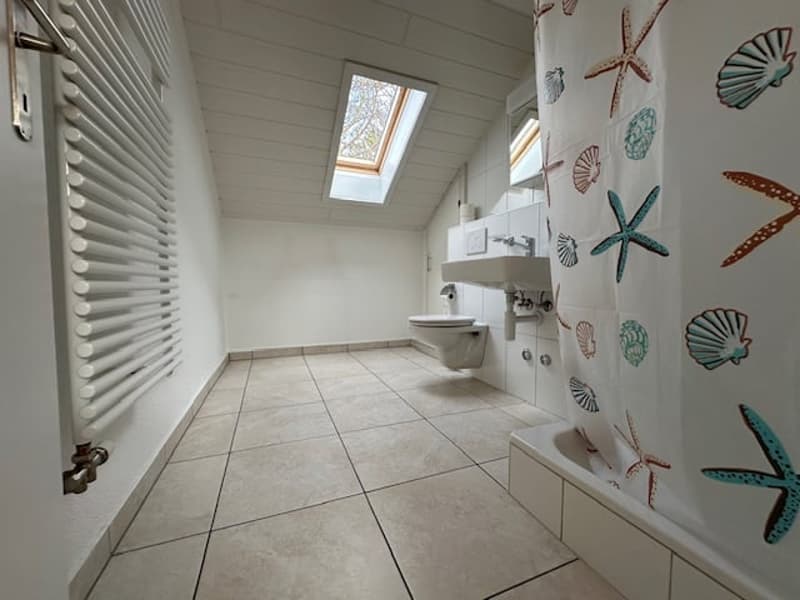 Bathroom with white tiles, white walls, white sink, white toilet, white bathtub, white shower curtain, white radiator, skylight