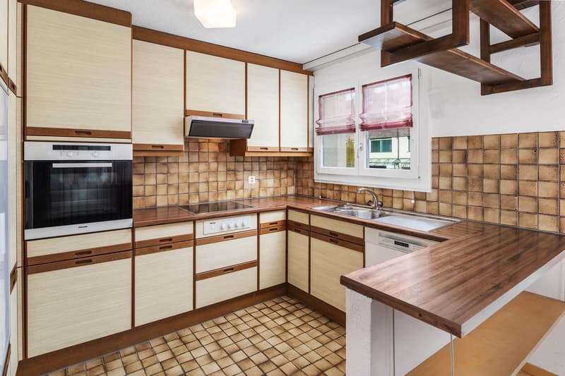 kitchen with tile flooring, wooden cabinets, integrated appliances, sink with faucet