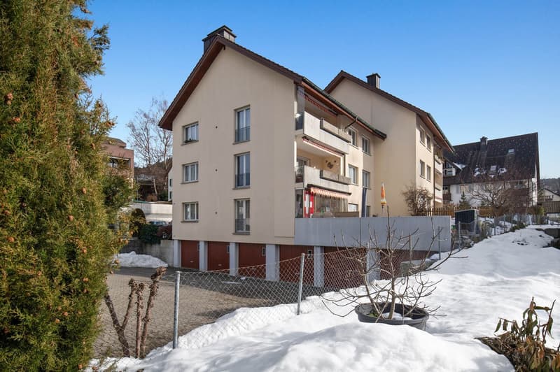 2 story house, raised ground floor, red brick walls, white windows, snow-covered area