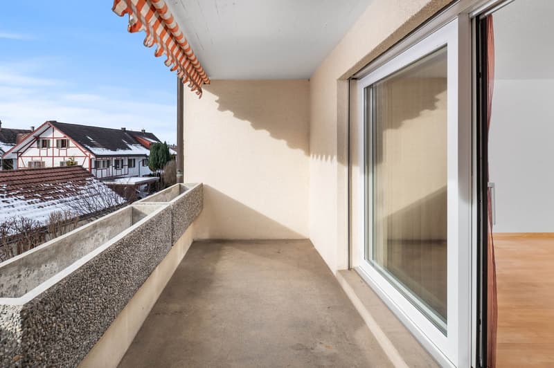 Empty balcony with concrete parapet and window overlooking the street