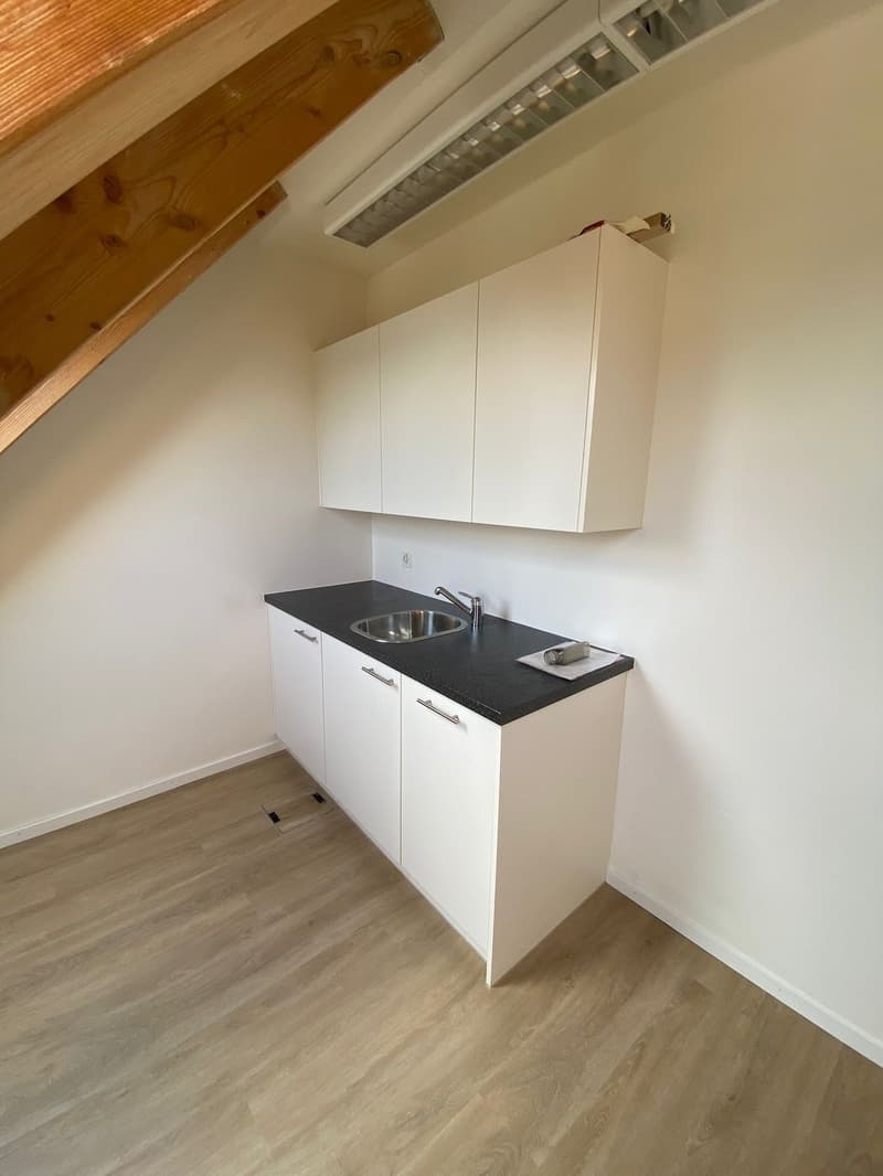 Empty kitchen with white cabinets, black countertops, a sink, and wooden floor