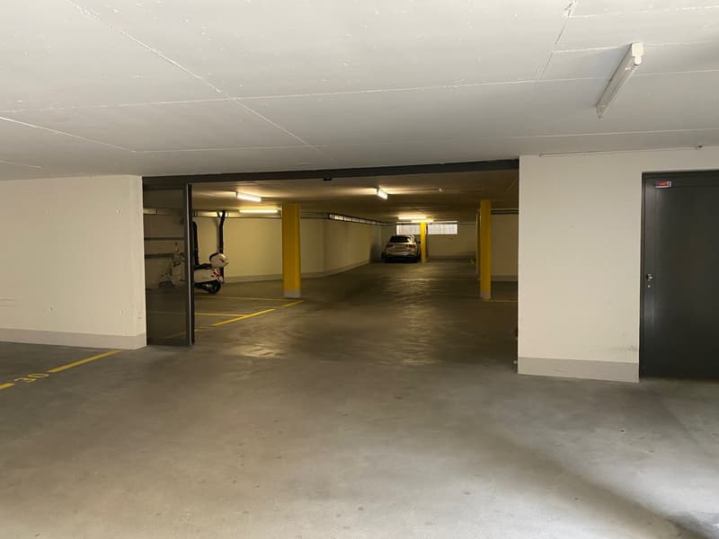 underground parking lot, yellow pillars, white walls, grey floor, parked car, scooter
