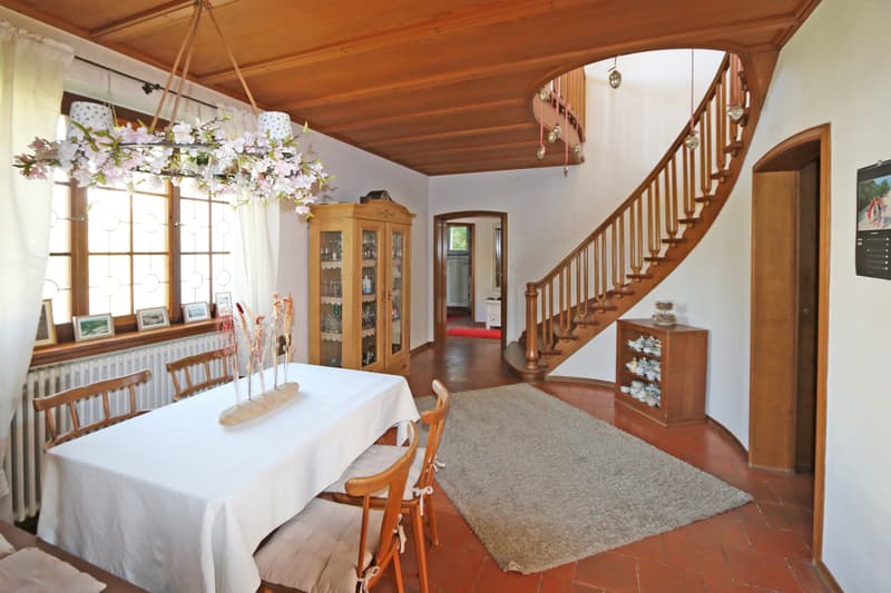 historische Halle mit Treppenaufgang  / a dining room with a white table and chairs and a wooden staircase to the second floor