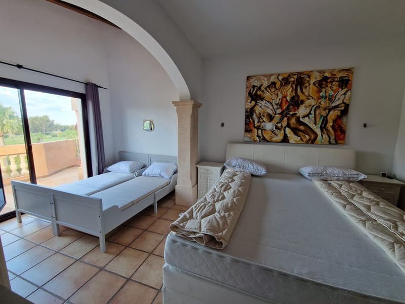 Bedroom with two single beds, sliding glass door leading to balcony, nightstands, wall painting, tiled floor.