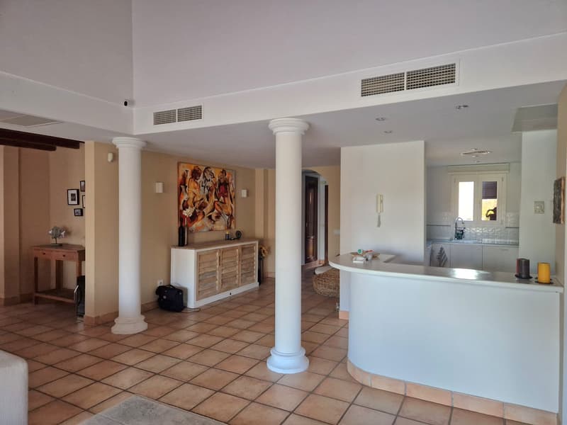 large open space, tile flooring, white ceiling, wooden cabinet, white countertops, kitchen area