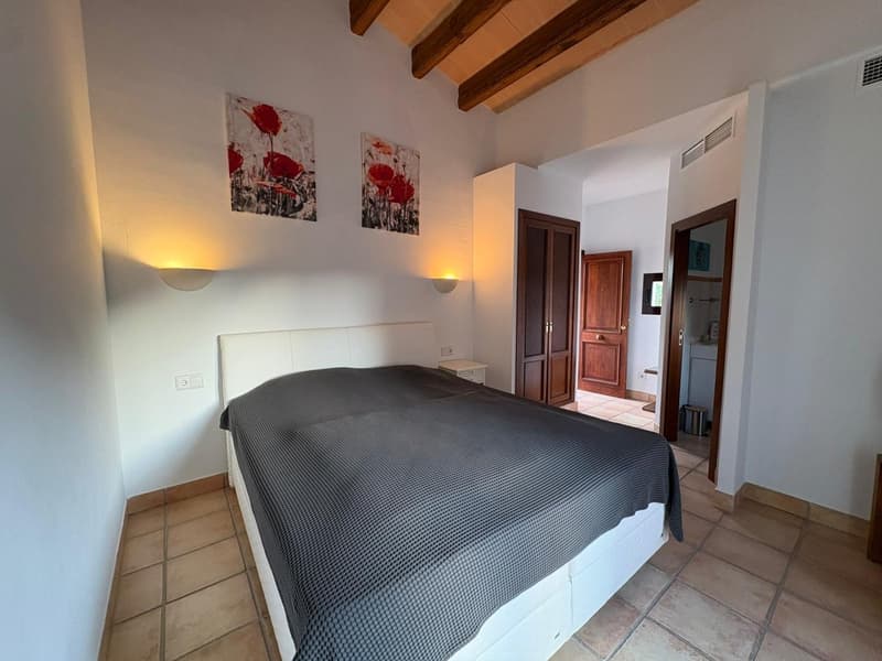 bedroom with bed, wall decor, ceiling lights, bathroom access, wooden doors