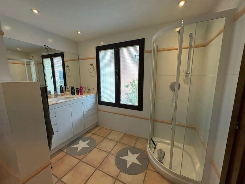 Shower, sink, cabinets, tiled floor, mirrors, window with blinds