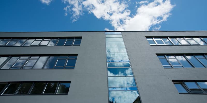 Modern office building, gray exterior, large windows, glass panels, multiple floors