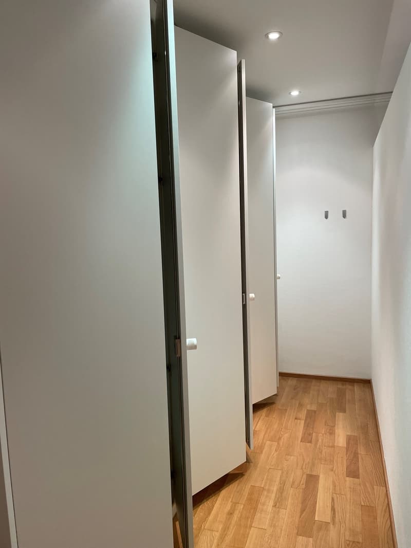 Hallway with white walls, wooden flooring, and built-in closets with sliding doors.