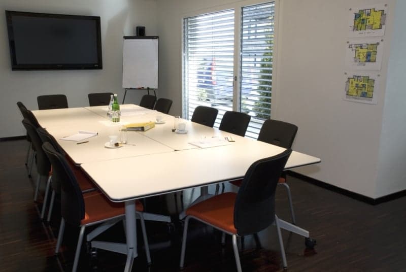 conference room with long table, chairs, whiteboard, TV, windows with blinds