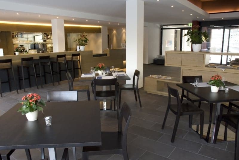 modern interior, black tables and chairs, wooden counter, flower vases, tiled floor