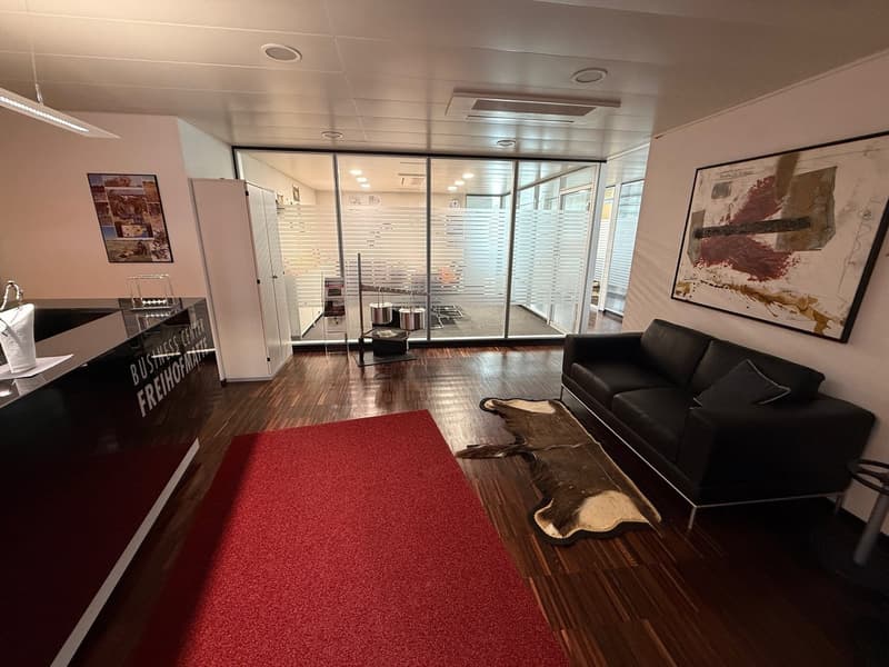 modern office space with black couch, red carpet, wooden floor, glass walls, artwork, reception desk