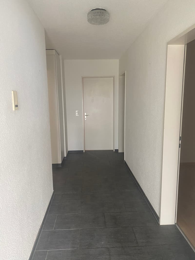 tiled floor, white walls, white ceiling, a white door with a silver handle, an electrical switch box mounted on the wall.