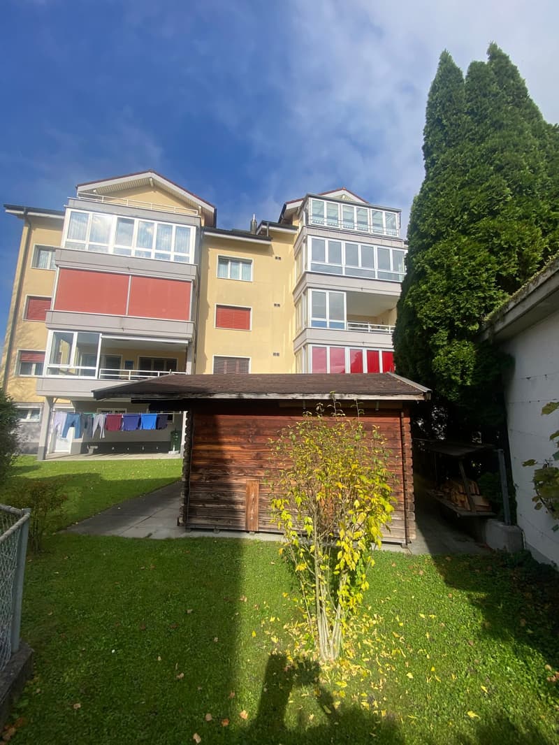 4-storey building with yellow exterior, 4 balconies, large lawn, small wooden house, clothesline