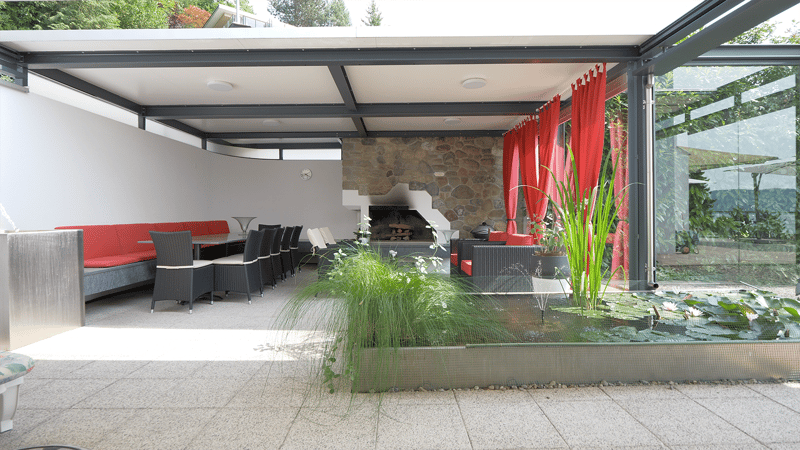 Patio area with stone and metal design, seating and dining area, fireplace, plants, and water feature.