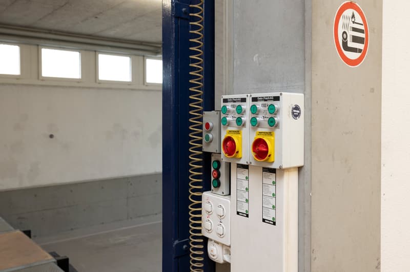 Control panel with multiple switches and buttons, mounted on a wall, with a spring mechanism and windows