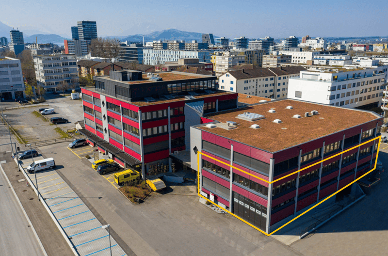 large office building, red and white color, multiple parking spaces, city view, several floors