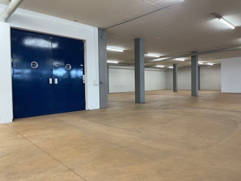 empty warehouse with large blue door and several supporting columns