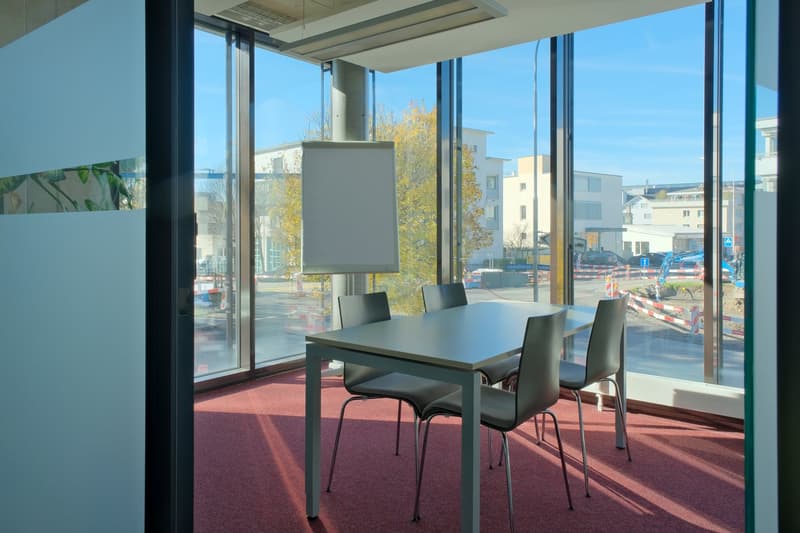 modern design meeting room with glass walls, gray table, gray chairs, whiteboard, red carpet