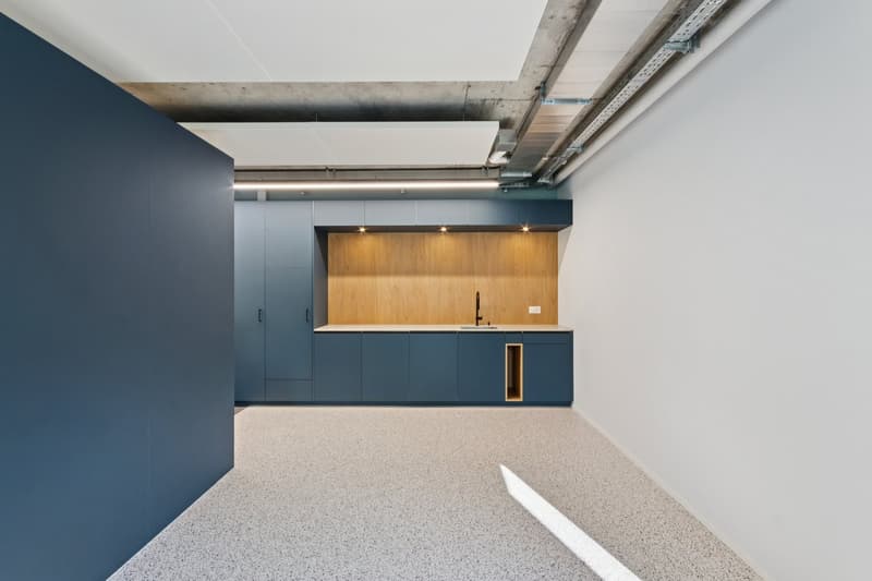 Modern kitchen with wooden countertops, blue cabinetry, a stainless steel faucet, a built-in sink, white walls, and speckled flooring