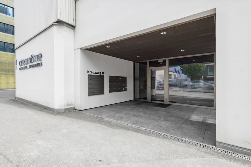 modern building entrance with mailboxes, glass doors, white walls, grey flooring, and a sign for dreamtime