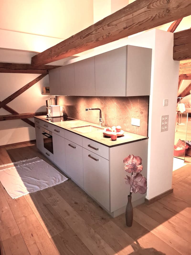 kitchen with wooden floor, modern kitchen setup with countertops, wooden beams, white cabinets, sink, faucet, modern stove, oven, dishwasher, wooden planks and flower vase