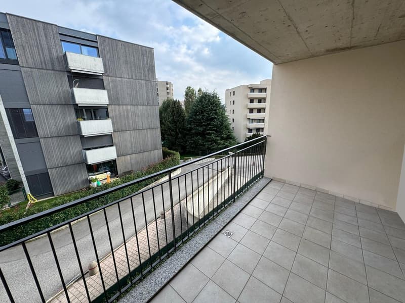 Balcony with tile flooring, overlooking a residential area with multi-story apartment buildings and trees