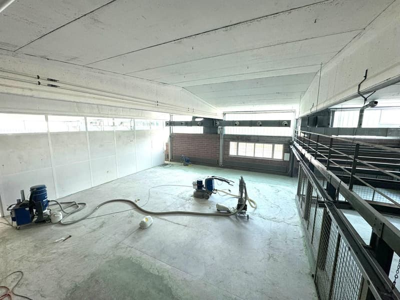 Empty room with white walls, concrete floor, and various equipment and tools on the ground.