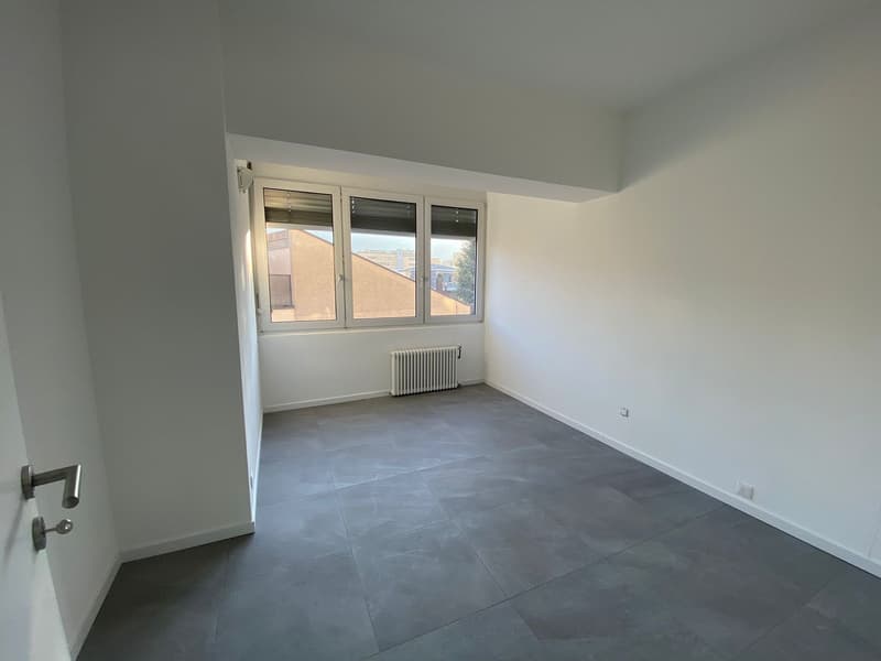 empty room, white walls, gray tile floor, window, radiator