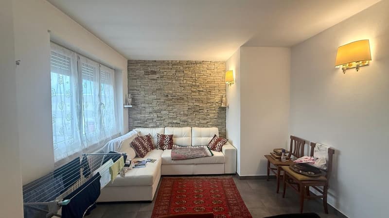 white sofa, red rug, stone wall, two chairs, lamps