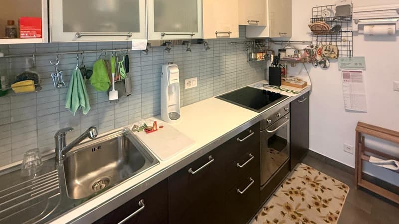 stainless steel sink, dishwasher, gas stove, oven, wooden counter, tile wall, hanging utensils, refrigerator, baskets, power outlet, cleaning products