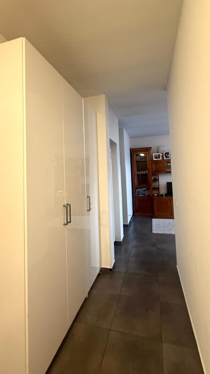 Hallway with a large white wardrobe and brown tiled floor.