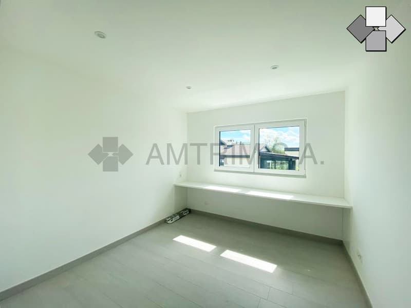Bright and spacious room with large windows, white walls, and a built-in window sill or bench.