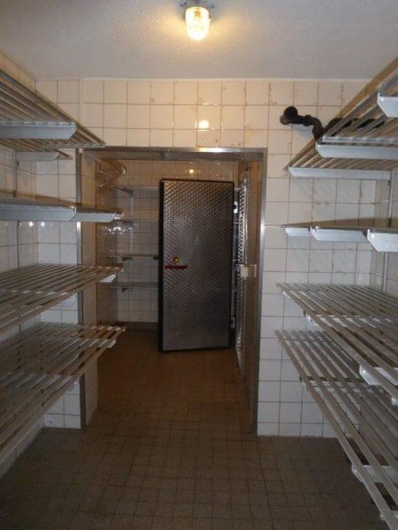 empty room with stainless steel racks, tiled walls, tiled floor, metal door