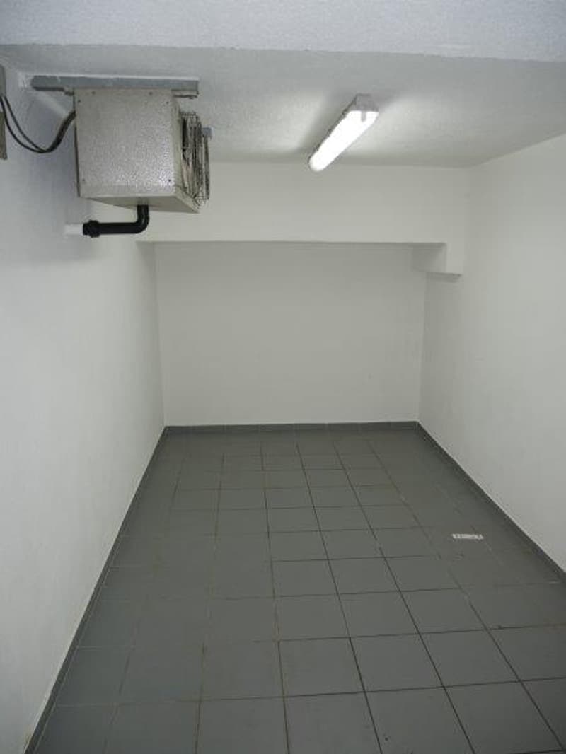 empty room with gray tiles, white walls, fluorescent light, air conditioning unit