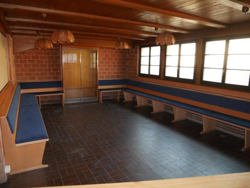 empty room, blue cushions on wooden benches, glass windows, brick wall, wooden ceiling, hanging lamps