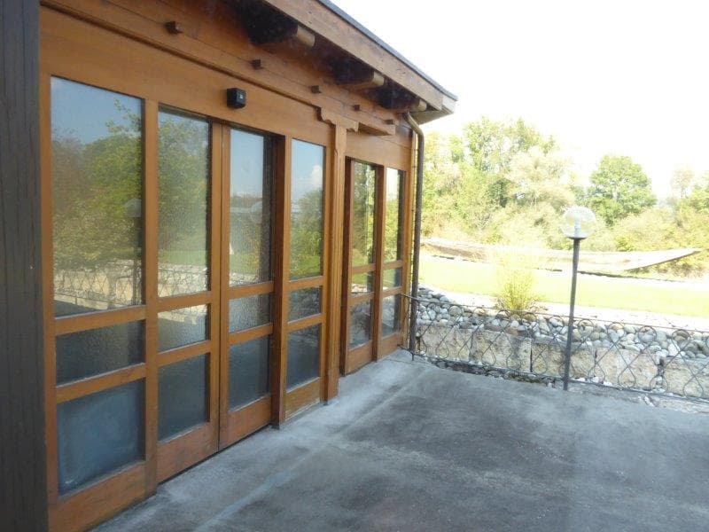 Terrace with wooden railing, large windows, view of the surrounding area.