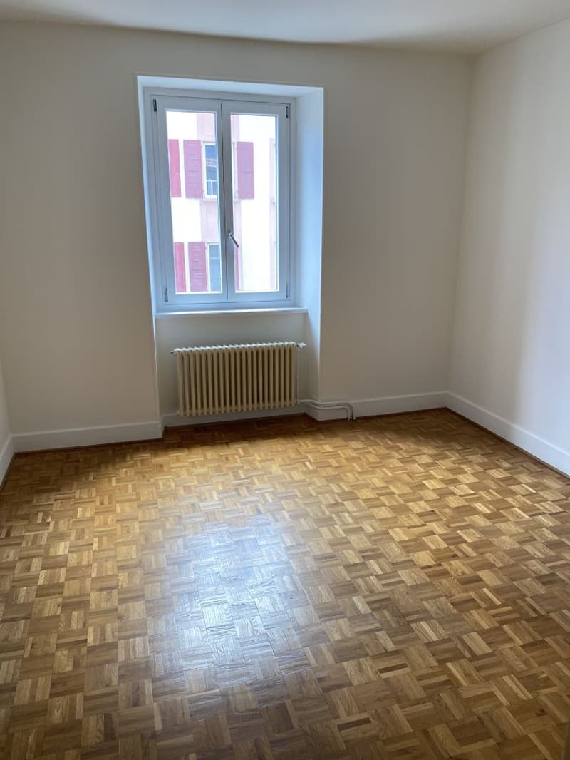 empty room, parquet flooring, white walls, window with shutters, radiator
