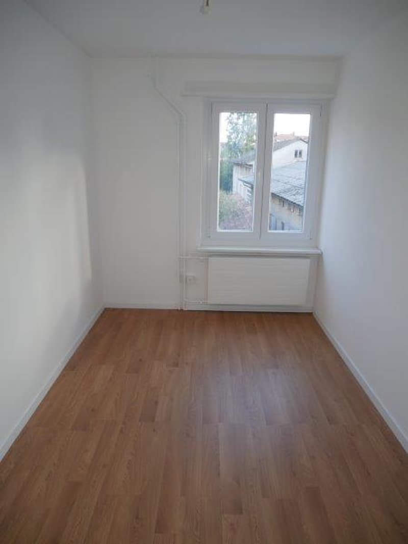 empty room with hardwood floors, white walls, windows, radiator