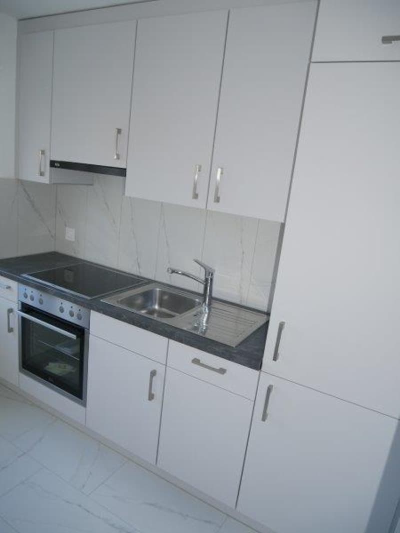 modern fitted kitchen with white cabinets, marble countertop, stainless steel sink, electric oven and hob, washing machine