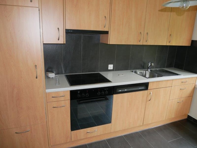 Fully equipped kitchen with light wood cabinets, black countertop, built-in oven and dishwasher, and a sink