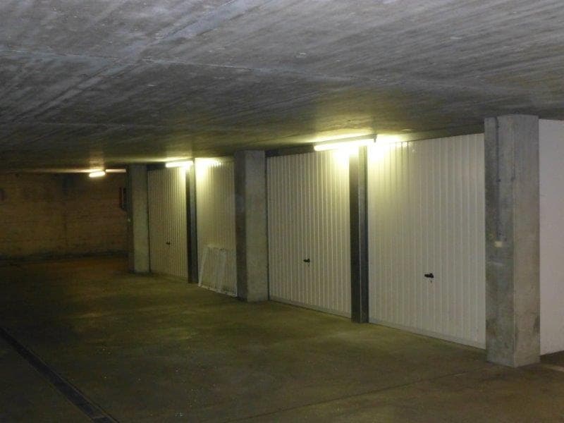 underground parking with large white garage doors, fluorescent lights on ceiling