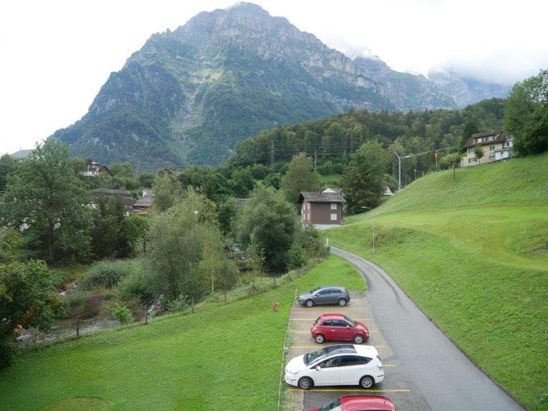 4 cars parked on an exterior parking lot with a nice view of the mountain.