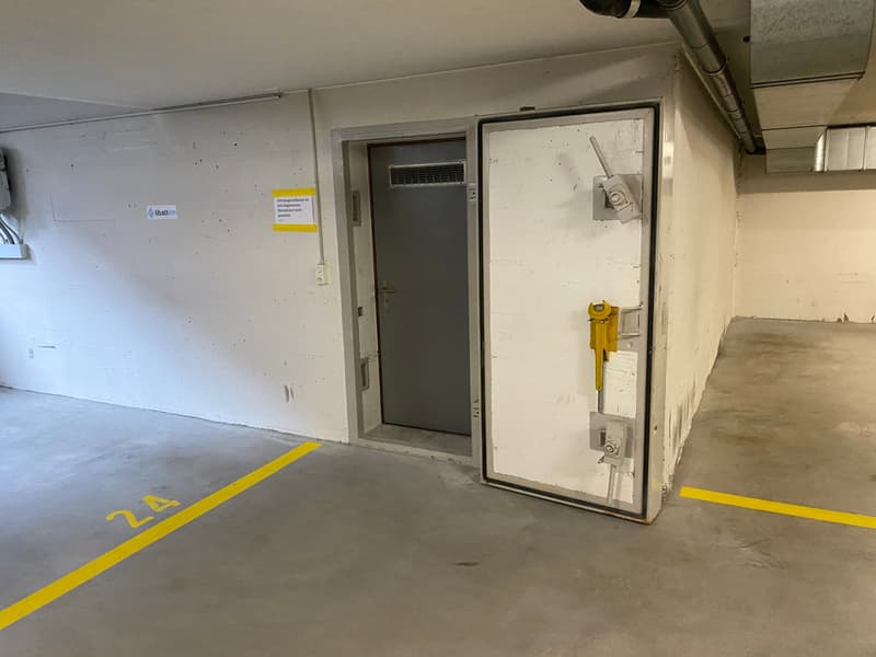 underground parking space, yellow line markings, grey walls, power outlet
